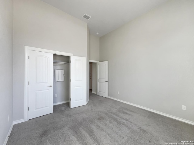 unfurnished bedroom featuring a towering ceiling, a closet, and carpet