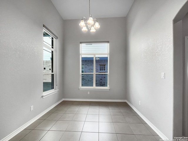 unfurnished room with a chandelier and light tile patterned floors