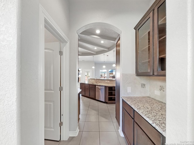 kitchen with light stone counters, dark brown cabinets, light tile patterned floors, dishwasher, and backsplash