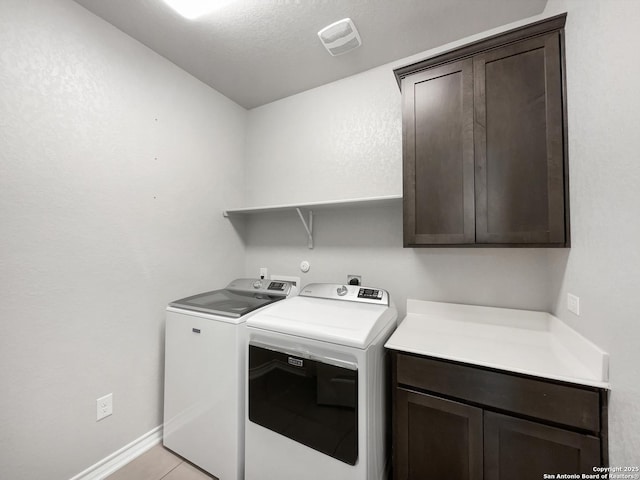 laundry room with cabinets, washing machine and clothes dryer, and light tile patterned floors