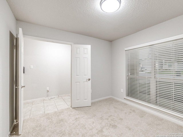 unfurnished bedroom with light colored carpet and a textured ceiling