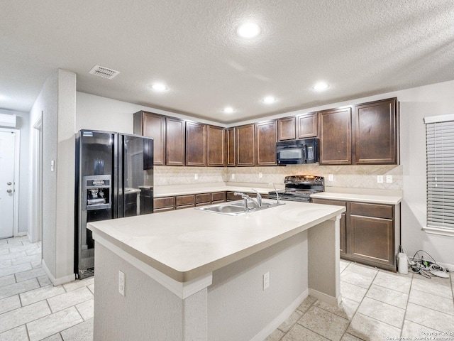 kitchen featuring sink, backsplash, black appliances, and an island with sink