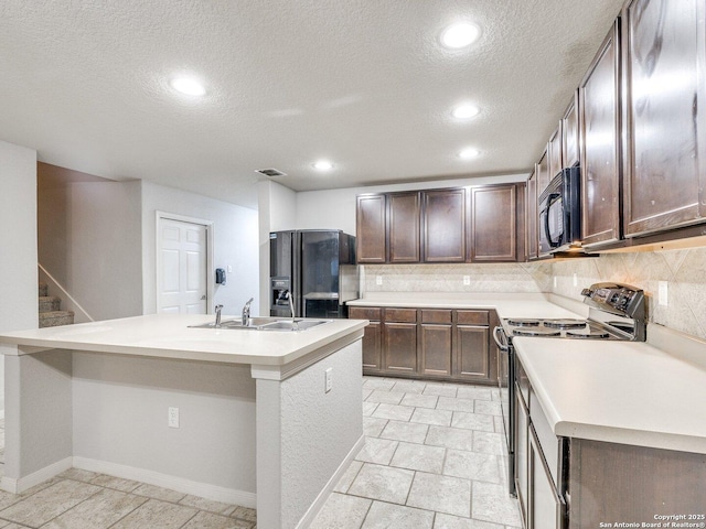 kitchen featuring sink, black appliances, dark brown cabinets, a kitchen island with sink, and backsplash