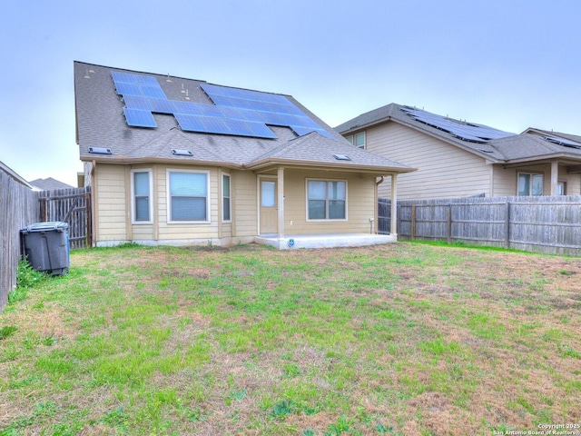 rear view of property with a yard, a patio, and solar panels