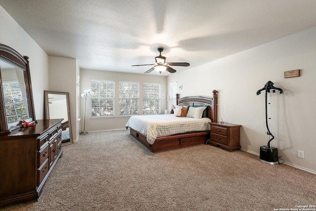 bedroom featuring ceiling fan, light colored carpet, and a textured ceiling