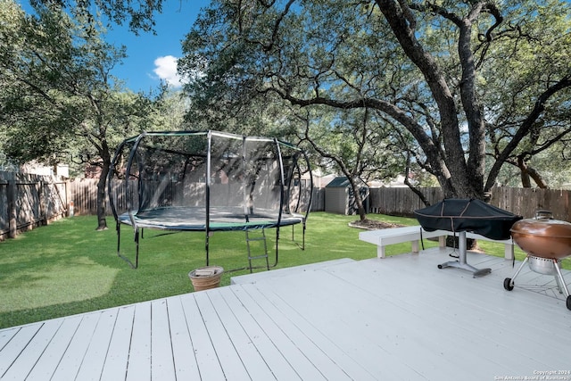 wooden deck with grilling area, a yard, and a trampoline