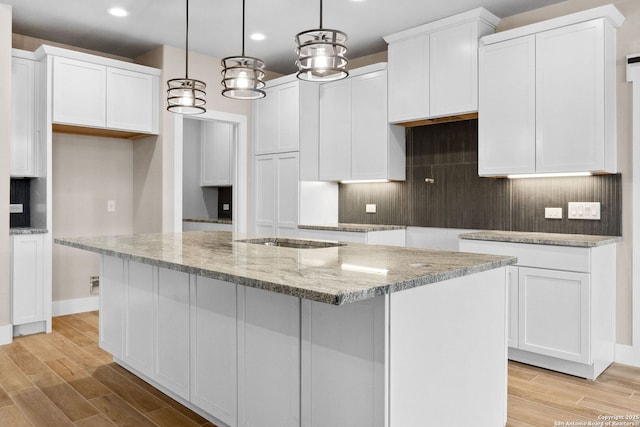 kitchen with pendant lighting, a center island with sink, and white cabinets