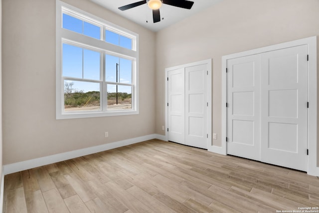 unfurnished bedroom with multiple closets, ceiling fan, and light wood-type flooring