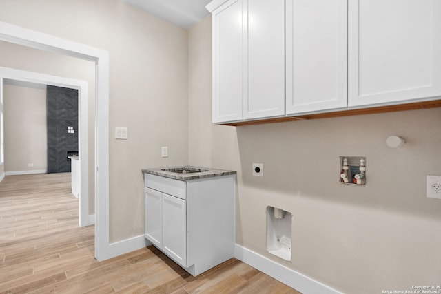 clothes washing area featuring cabinets, hookup for an electric dryer, and light hardwood / wood-style flooring