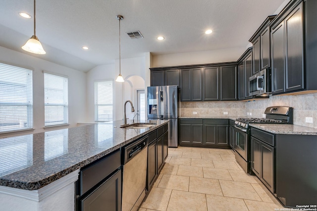 kitchen with appliances with stainless steel finishes, decorative light fixtures, sink, and dark stone countertops