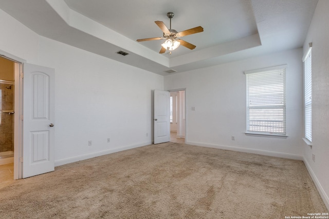 spare room featuring ceiling fan, a raised ceiling, and light carpet