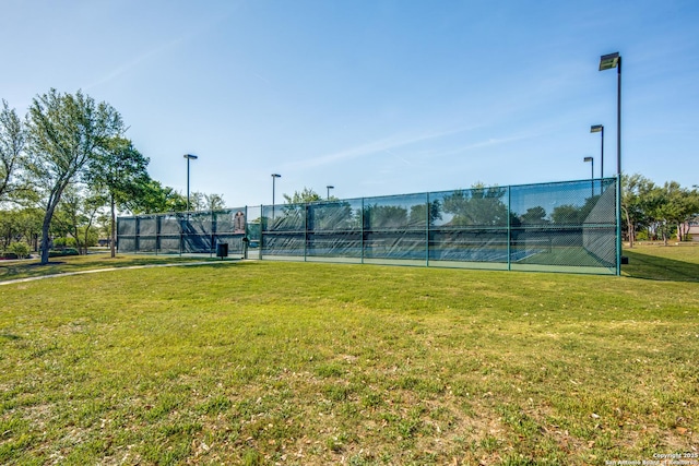 view of tennis court featuring a lawn