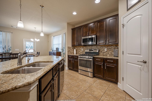 kitchen with appliances with stainless steel finishes, decorative light fixtures, sink, dark brown cabinetry, and light stone counters