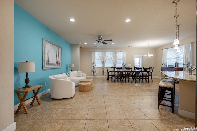 living room with plenty of natural light, ceiling fan with notable chandelier, and light tile patterned floors