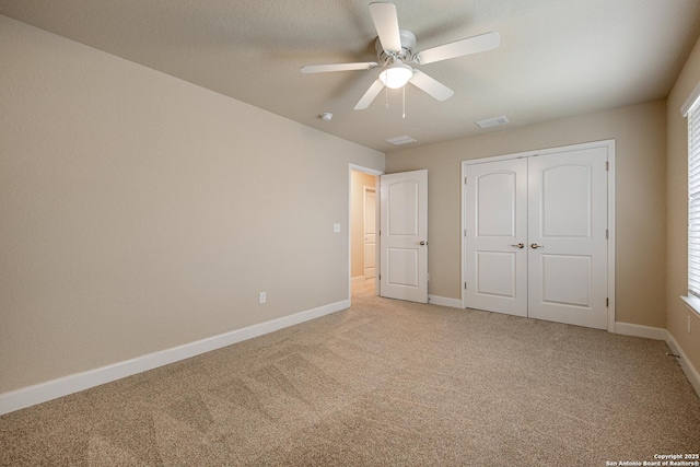 unfurnished bedroom featuring light colored carpet, ceiling fan, and a closet