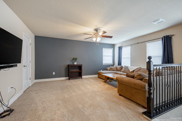 living room featuring light carpet, ceiling fan, and a textured ceiling