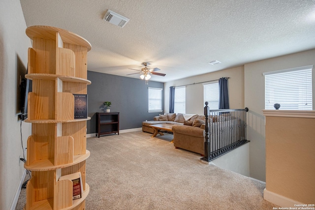 carpeted living room featuring ceiling fan and a textured ceiling