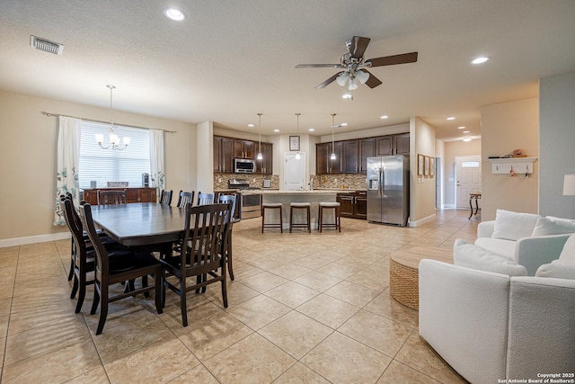 tiled dining space featuring ceiling fan with notable chandelier