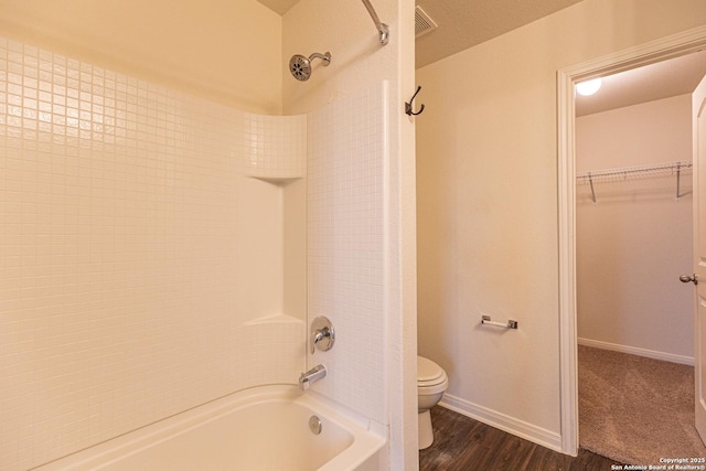 bathroom with wood-type flooring, toilet, and tub / shower combination