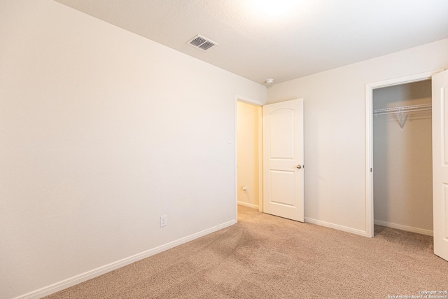 unfurnished bedroom featuring light colored carpet and a closet