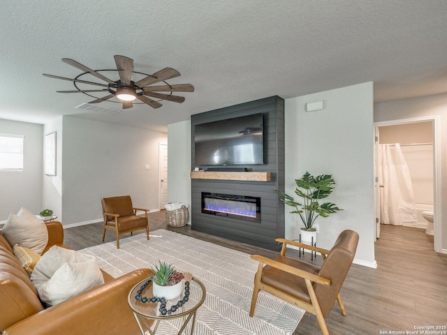 living room with hardwood / wood-style flooring, a textured ceiling, and a fireplace