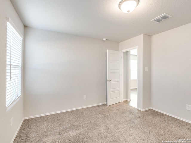 unfurnished room featuring carpet and a textured ceiling