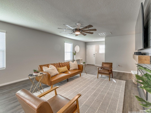 living room with dark hardwood / wood-style flooring, a textured ceiling, and ceiling fan