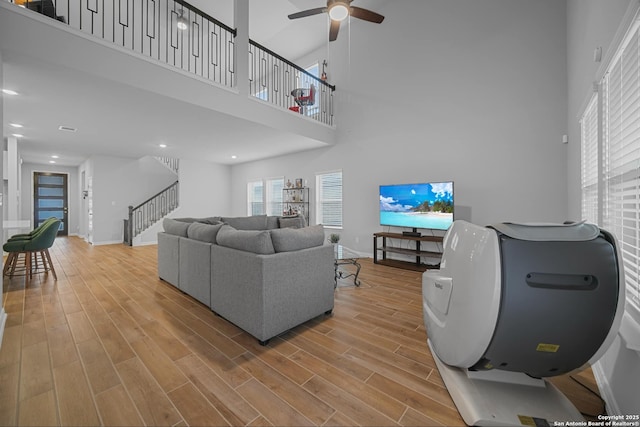 living room featuring a high ceiling, hardwood / wood-style floors, and ceiling fan