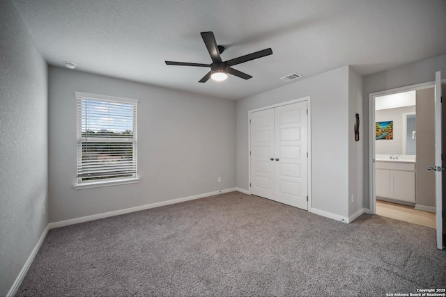 unfurnished bedroom featuring ceiling fan, a closet, light carpet, and a textured ceiling