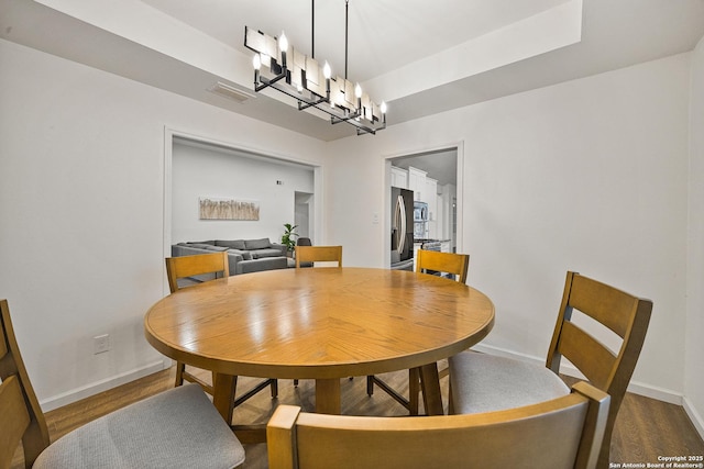 dining room with hardwood / wood-style floors and an inviting chandelier