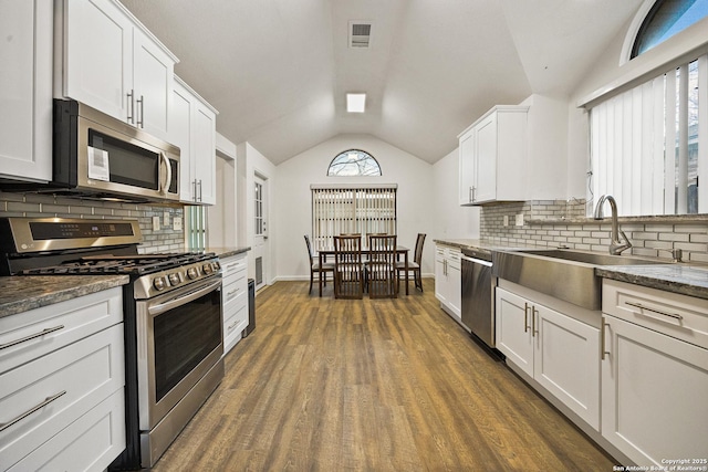 kitchen featuring lofted ceiling, dark hardwood / wood-style floors, stainless steel appliances, decorative backsplash, and white cabinets