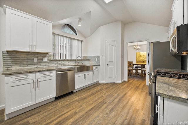 kitchen with white cabinetry, appliances with stainless steel finishes, sink, and dark stone countertops