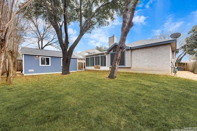 back of property featuring central AC unit, a yard, and a sunroom