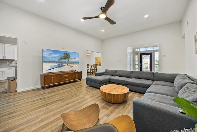 living room featuring light hardwood / wood-style flooring, ceiling fan, and a high ceiling