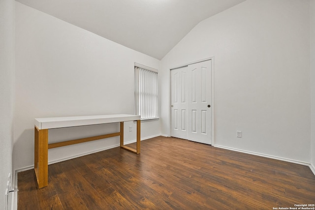 unfurnished bedroom featuring dark hardwood / wood-style flooring, lofted ceiling, and a closet