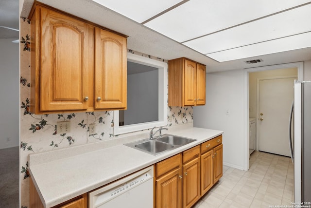 kitchen with white dishwasher, sink, and stainless steel refrigerator