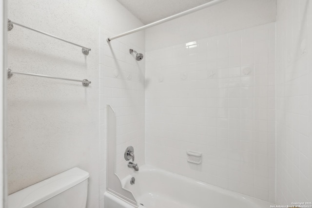 bathroom with toilet and tiled shower / bath