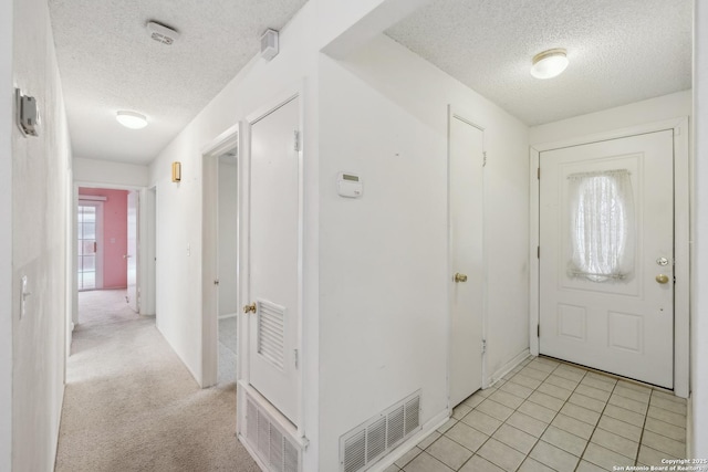 foyer entrance featuring light colored carpet and a textured ceiling