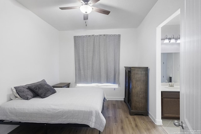 bedroom featuring sink, ensuite bath, light hardwood / wood-style flooring, and ceiling fan