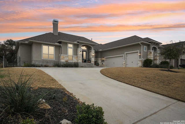 view of front of home with a yard, a chimney, stucco siding, an attached garage, and driveway