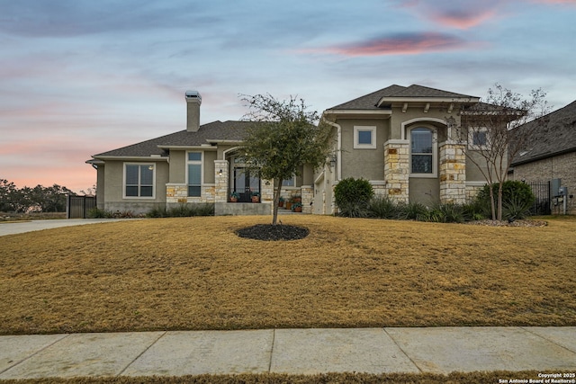 view of front of house featuring a yard, a chimney, and stucco siding