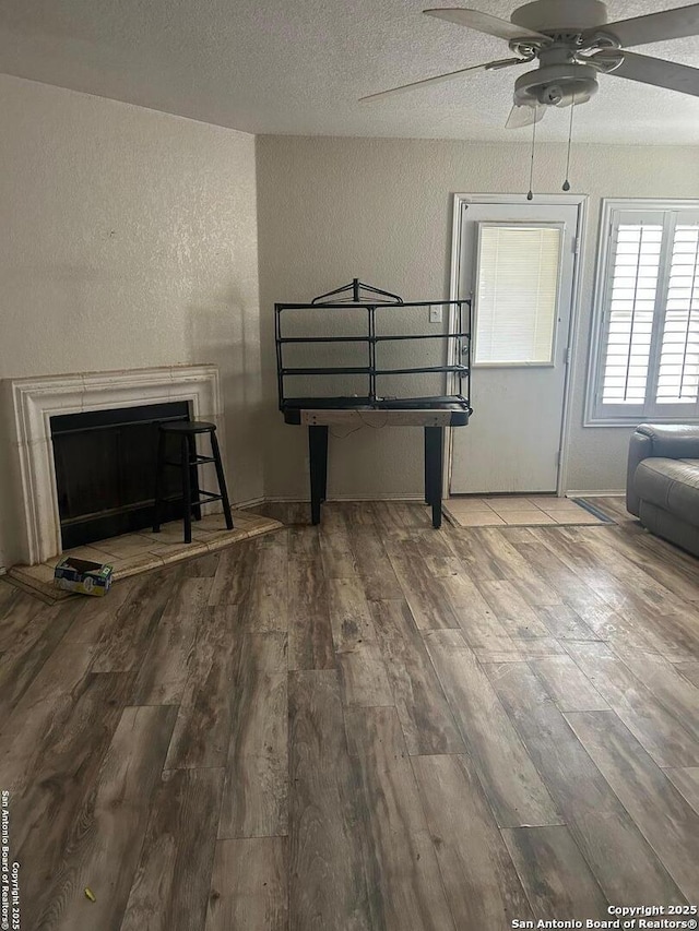 25710 Presidio Aly, Boerne, TX 78015 - unfurnished living room featuring a textured ceiling, a fireplace with raised hearth, ceiling fan, a textured wall, and hardwood / wood-style flooring