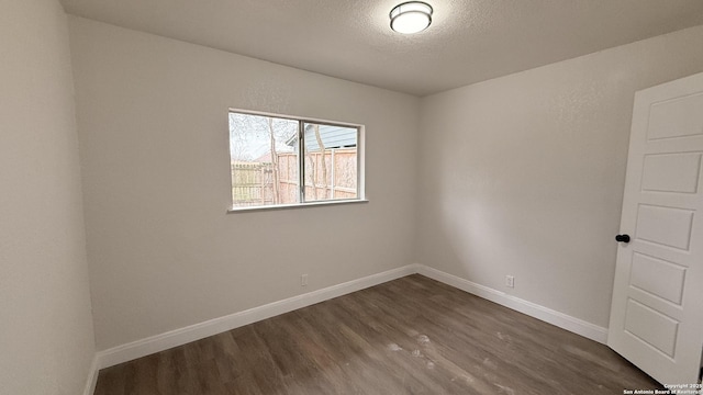 spare room featuring dark hardwood / wood-style floors and a textured ceiling