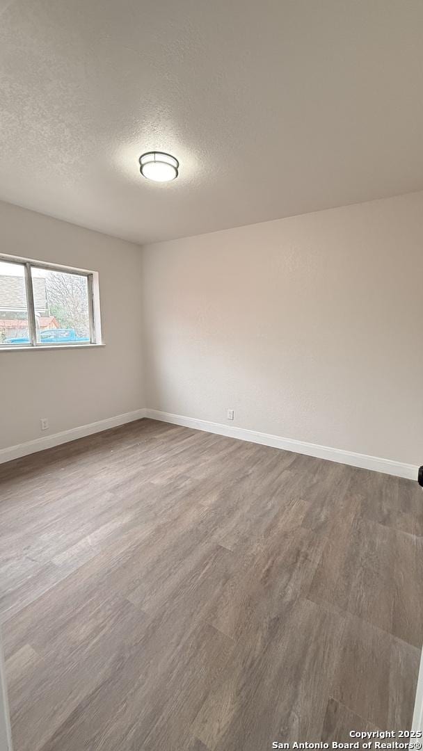 spare room featuring wood-type flooring and a textured ceiling