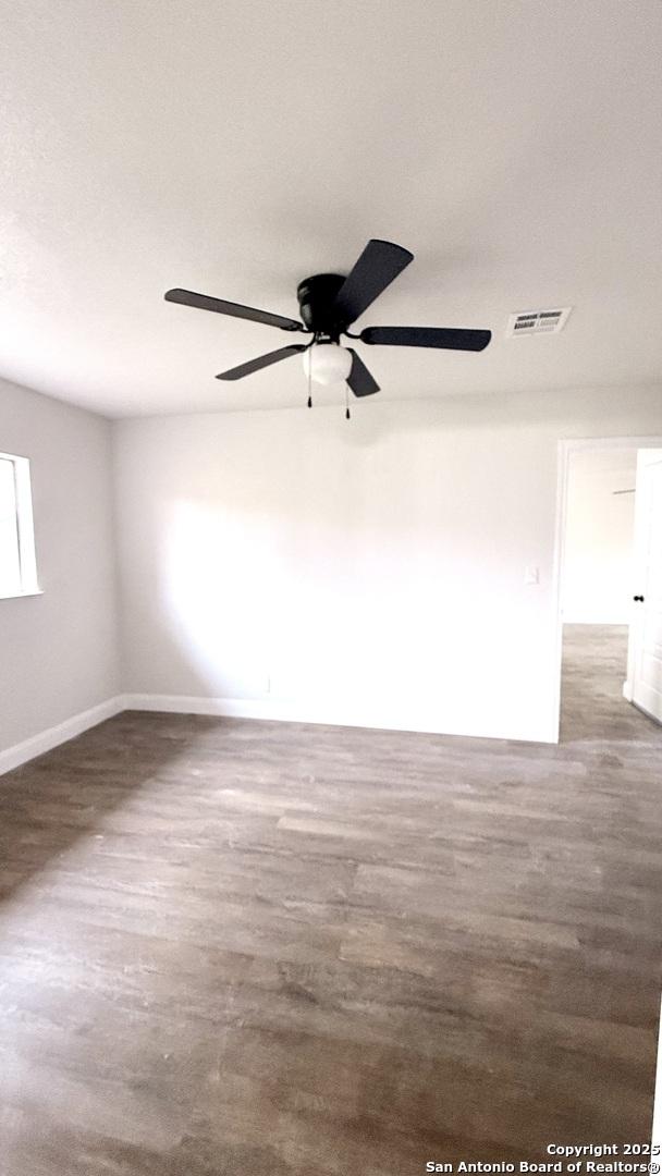 empty room featuring dark wood-type flooring and ceiling fan