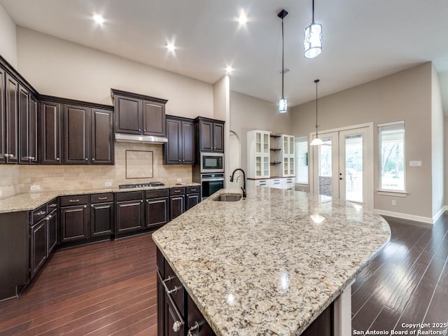 kitchen featuring hanging light fixtures, dark brown cabinets, a large island, and backsplash