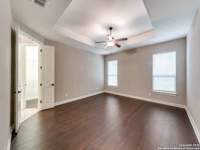 unfurnished room featuring a tray ceiling, dark hardwood / wood-style floors, and ceiling fan