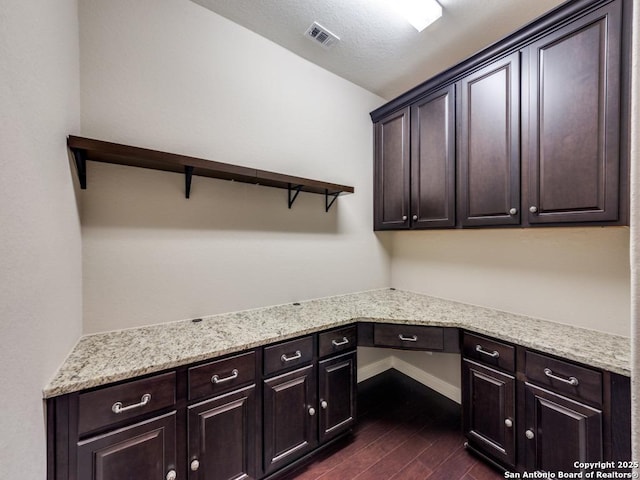 unfurnished office featuring built in desk, a textured ceiling, and dark hardwood / wood-style flooring