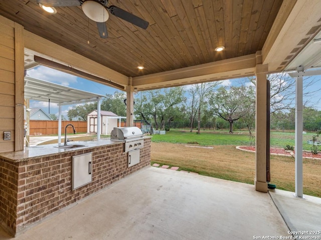 view of patio / terrace with an outdoor kitchen, sink, grilling area, and a shed