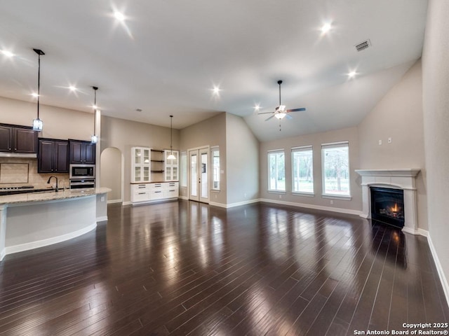 unfurnished living room featuring sink, vaulted ceiling, dark hardwood / wood-style floors, and ceiling fan